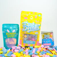yellow bunny poop mini bombs bag, blue bunny dust bag, and bunny buddies mini soap jar on top of a pile of bunny buddies mini soaps