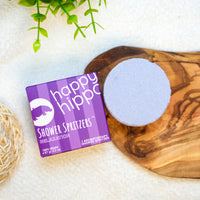 Happy Hippo Shower Spritzers packaging with a bath bomb on a wooden board.
