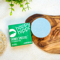 Happy Hippo Shower Spritzer packaging with a blue circular spritzer on a wooden surface.