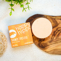 Happy Hippo Shower Spritzers packaging on a wooden tray with a plant in the background