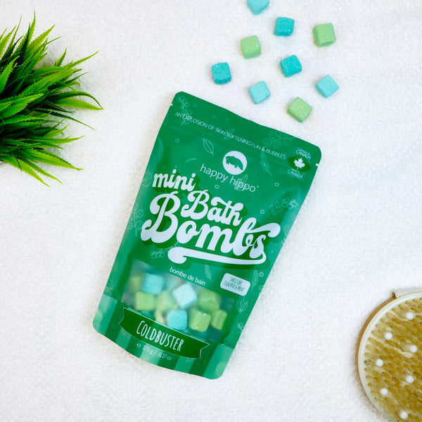 Green Coldbuster Mini Bath Bombs bag on a white background with bath bombs on a towel