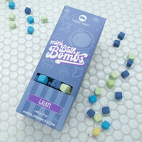 Blue Box of Galaxy Mini Bath Bombs on a white background with bath bombs scattered around it