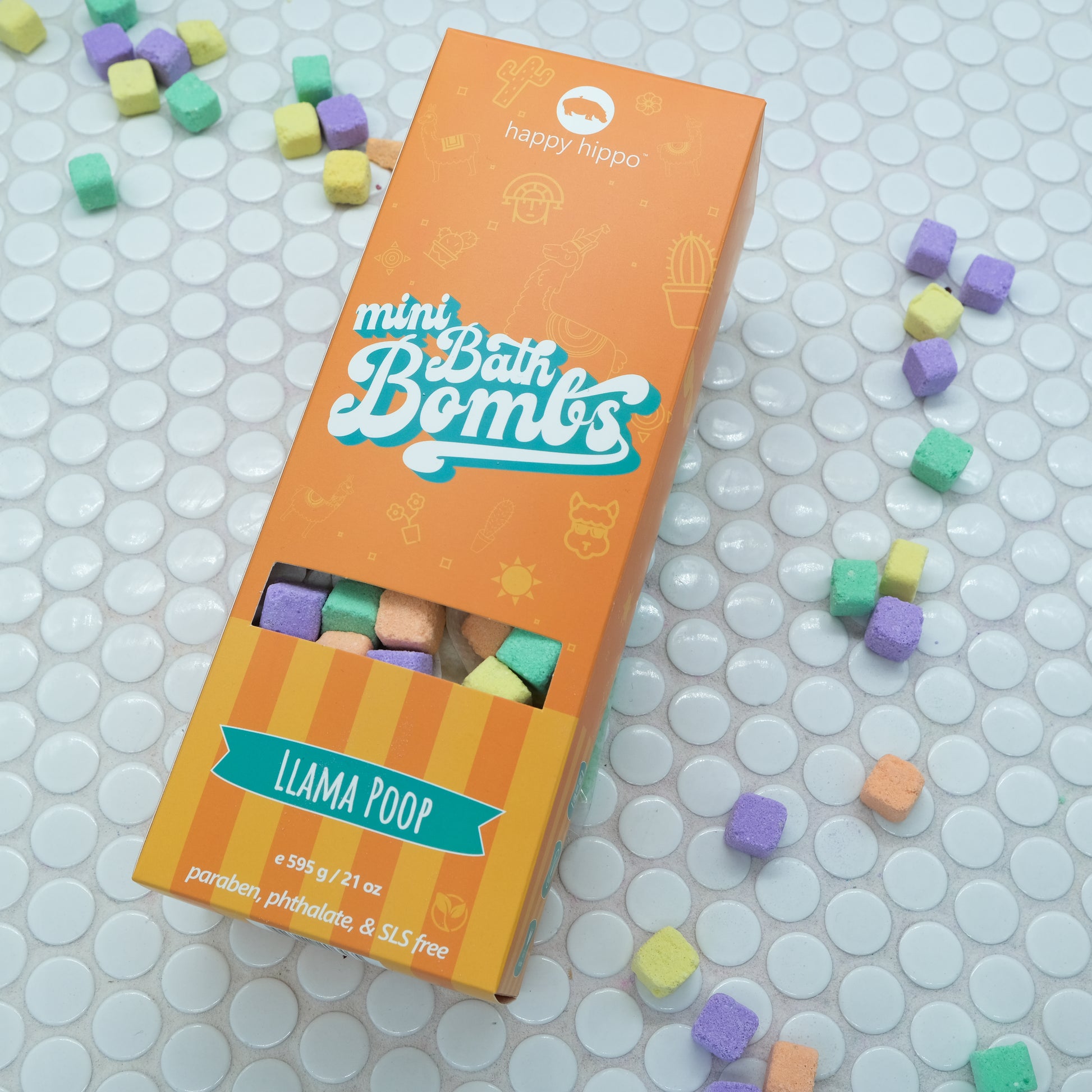Orange box of Llama Poop Mini Bath Bombs on a white background with bath bombs scattered around it