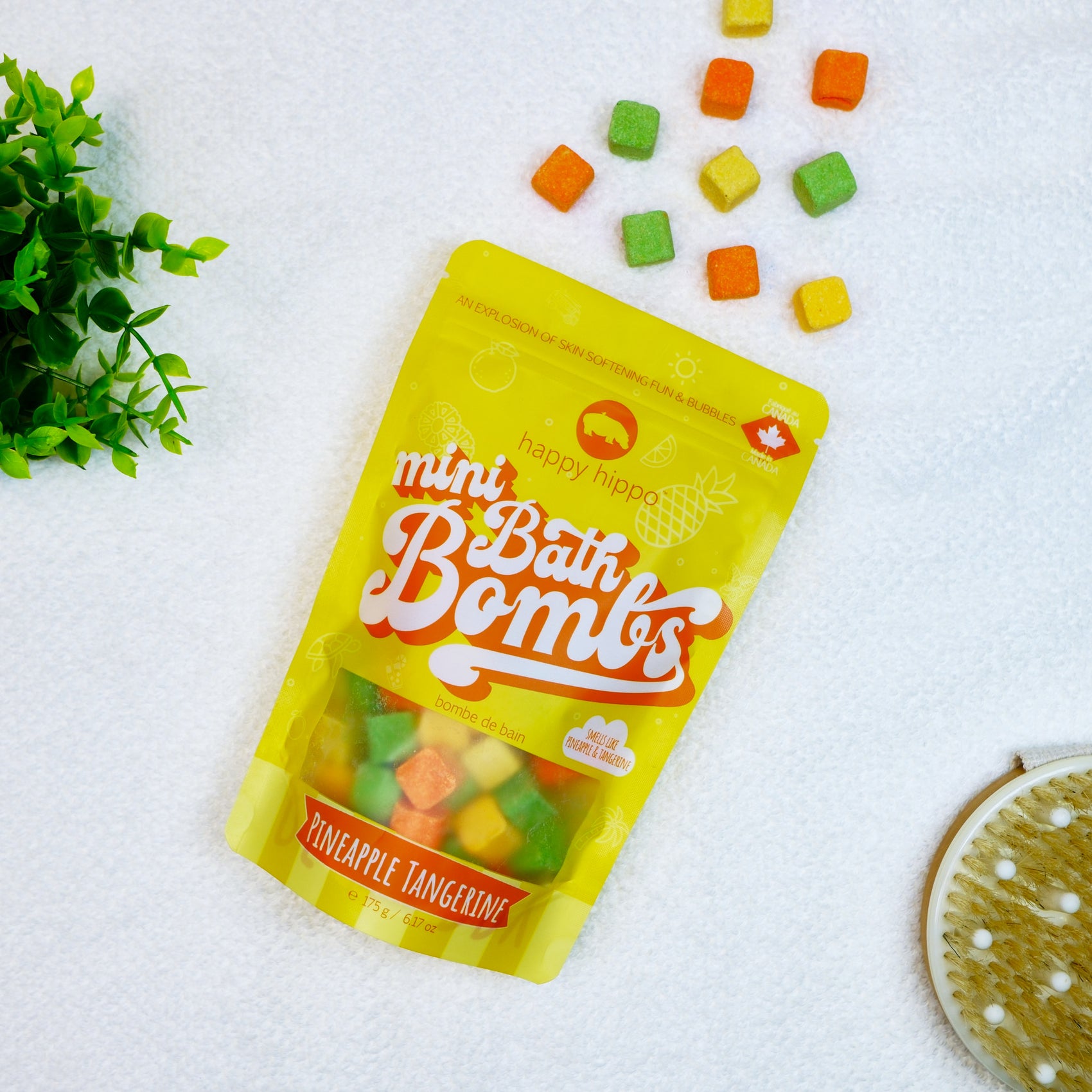 Bag of yellow and orange Pineapple Tangerine Mini Bath Bombs on a white background with mini bath bombs scattered around it