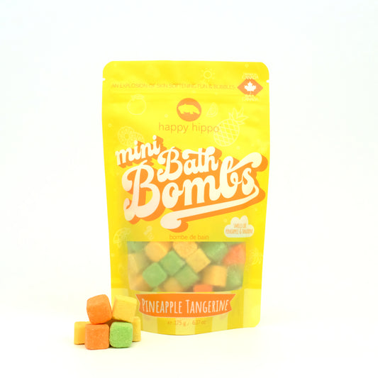 Bag of yellow and orange Pineapple Tangerine Mini Bath Bombs on a white background with mini bath bombs stacked in front of it