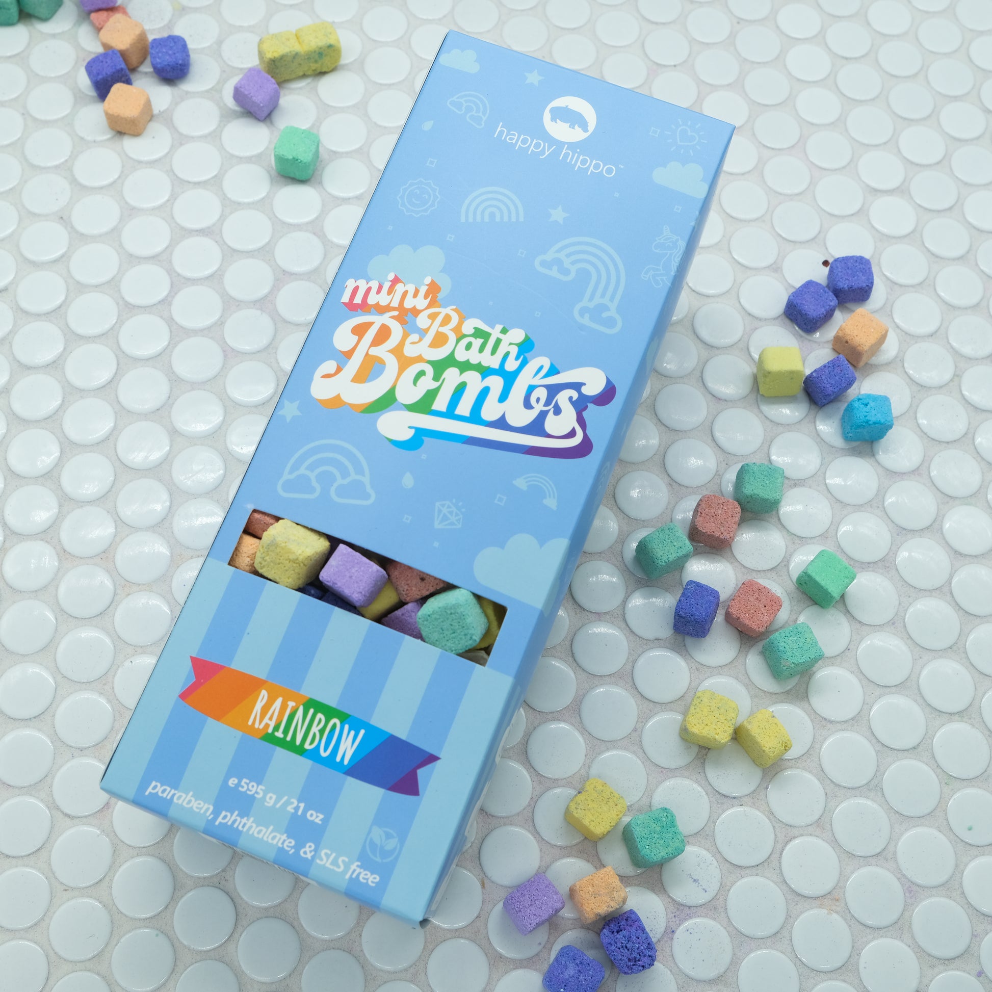 Light blue box of Rainbow Mini Bath Bombs on a white background with bath bombs scattered around it