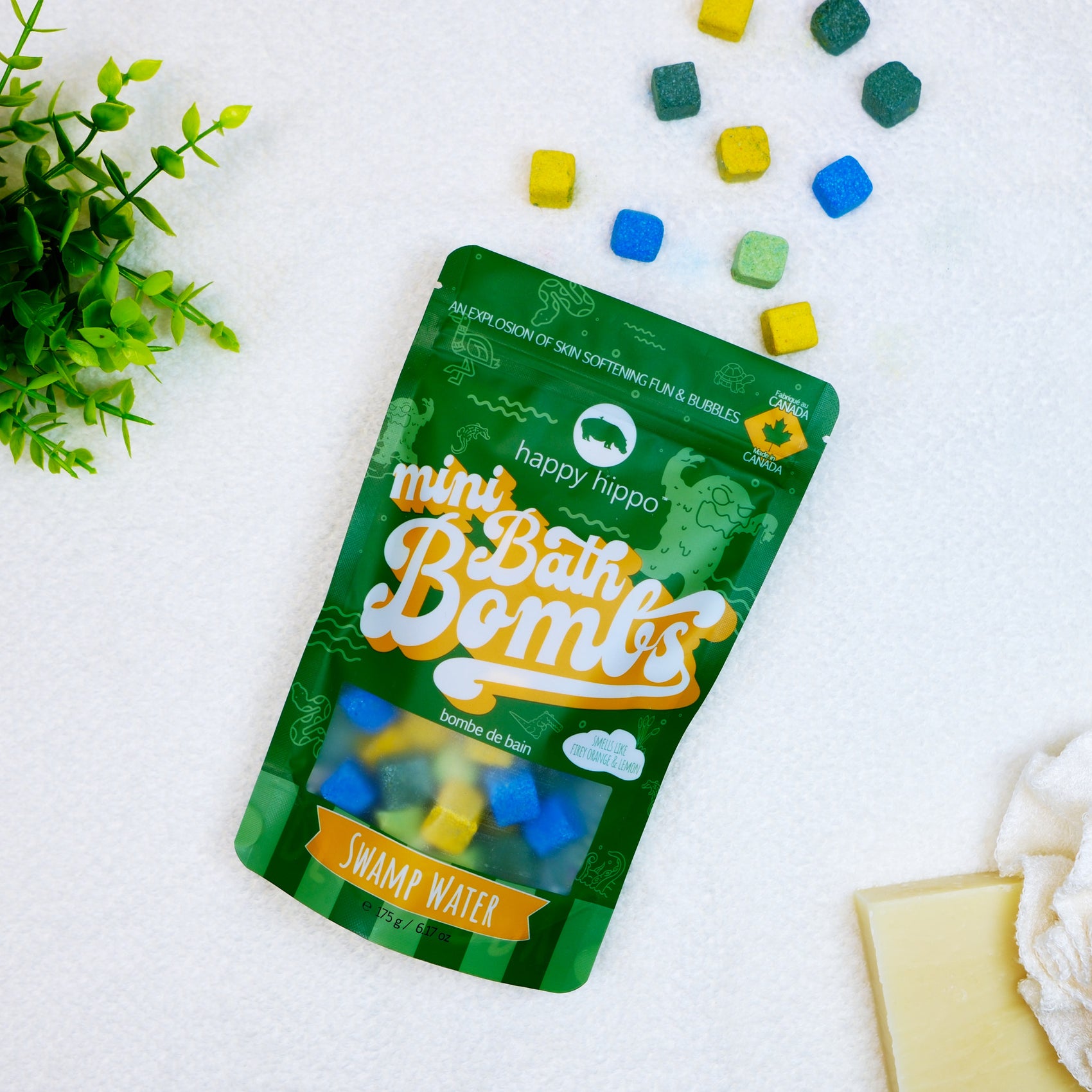 Bag of green Swamp Water Mini Bath Bombs on a white background with mini bath bombs scattered around it