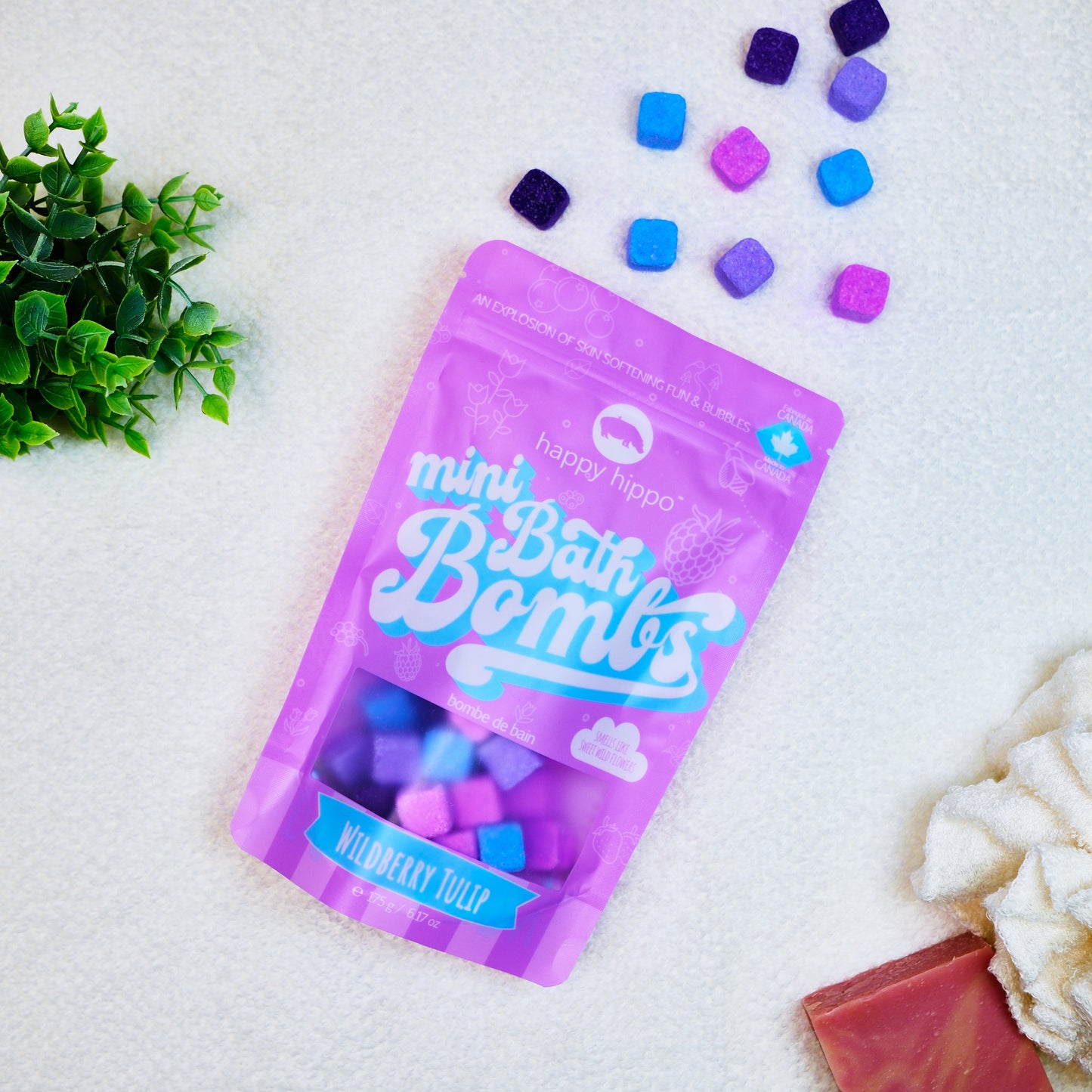 Bag of pink Wildberry Tulip Mini Bath Bombs on a white background with mini bath bombs scattered around it