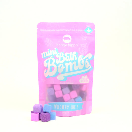 Bag of pink Wildberry Tulip Mini Bath Bombs on a white background with mini bath bombs stacked in front of it. 