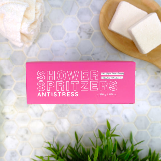 Shower Spritzers pink antistress packaging on a marble surface with spritzers and plants