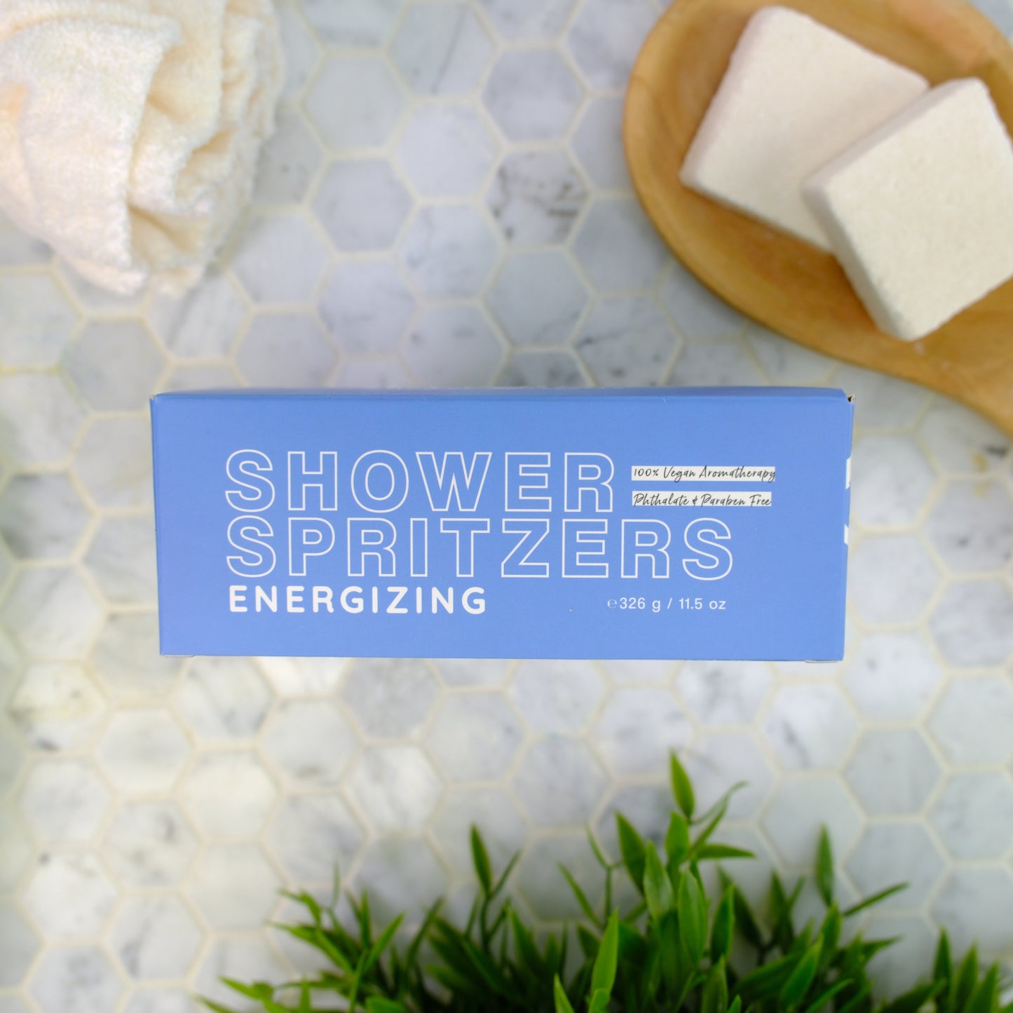 Shower spritzers packaging labeled 'energizing' on a marble surface with spritzers and greenery.