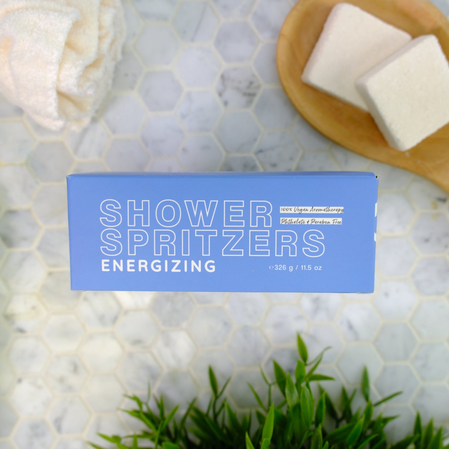Shower spritzers packaging labeled 'energizing' on a marble surface with spritzers and greenery.